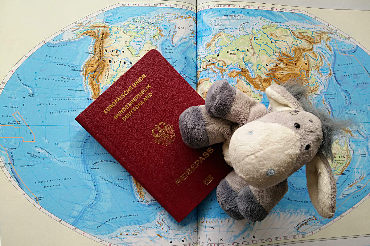 Der Esel unterwegs mit Reisepass und Weltkarte